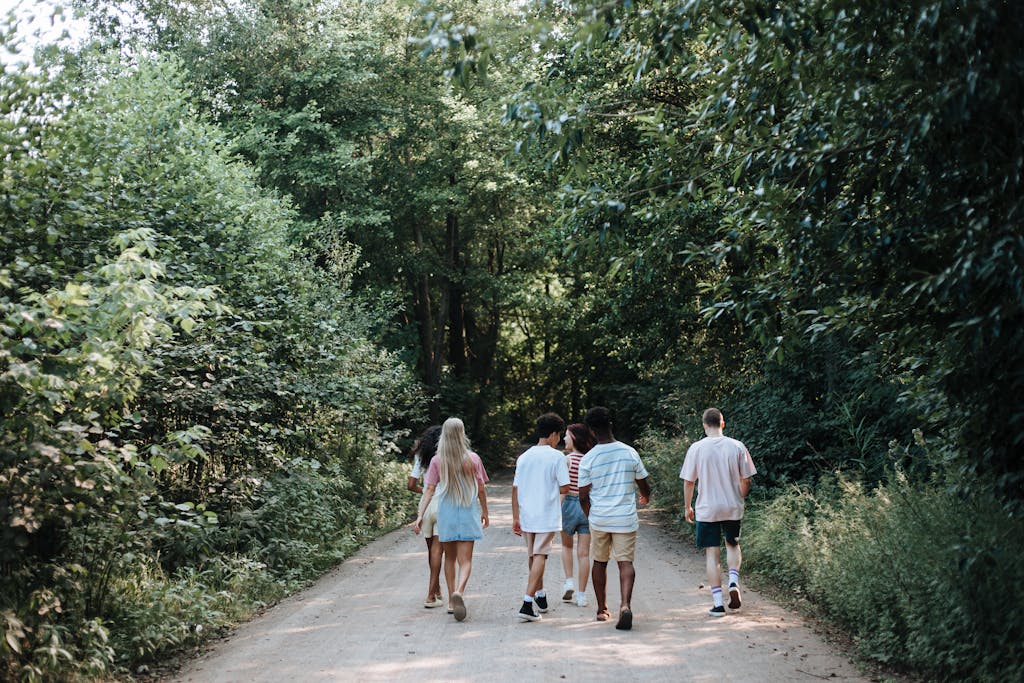 A group of teenagers walking on a forest trail, embracing nature and friendship.